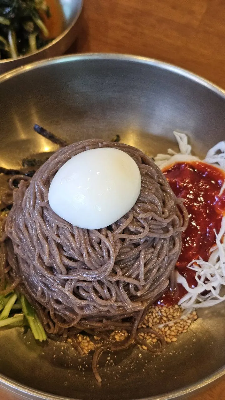 면 옆에 붉은 양념과 채소가 담긴 살구실 비빔막국수